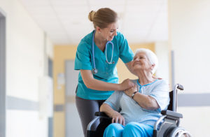 Infirmière souriant avec une femme en fauteuil roulant