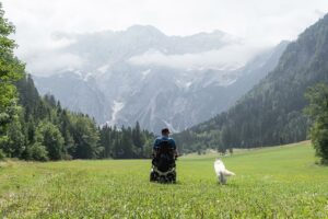 Homme handicapé en fauteuil roulant et son chien se promenant en montagne