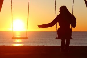 Femme sur une balançoire regardant la balançoire vide à côté d'elle