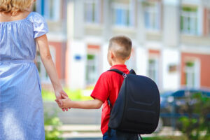 Enfant portant un sac à dos accompagné de sa mère