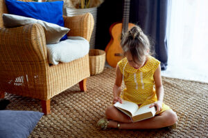 Fille assise sur le sol en train de lire un livre